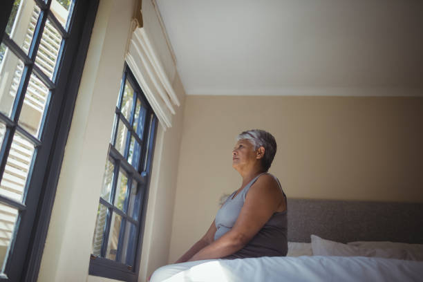 istock Thoughtful senior woman looking through window in bed room 800505112
