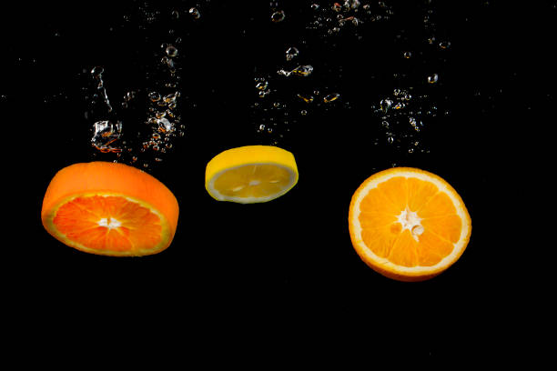 istock lemon and orange splashing in water on dark background 800832292