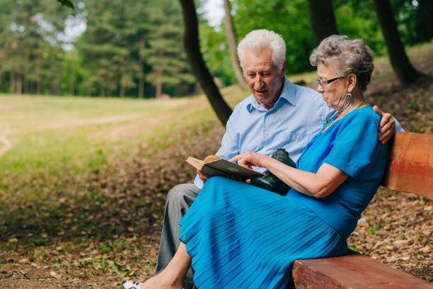istock Seniors spending summer afternoon in park and reading book together 800866792