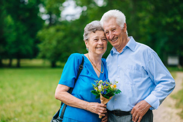 istock Charming senior couple with flowers in park 800868400