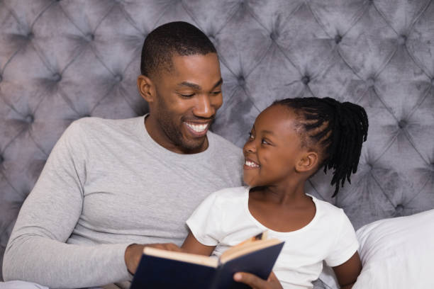 istock Happy man with daughter reading book on bed 800887026