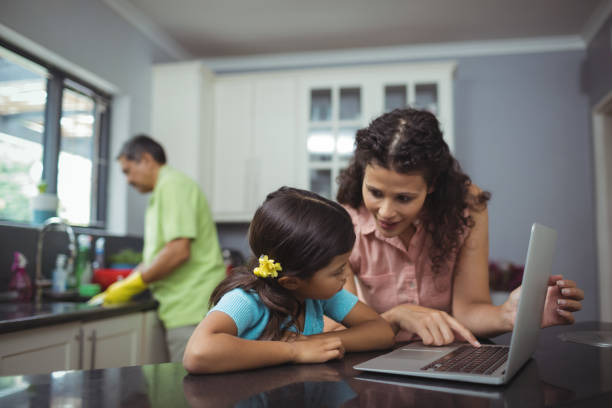 istock Mother and daughter using laptop in kitchen 800920004