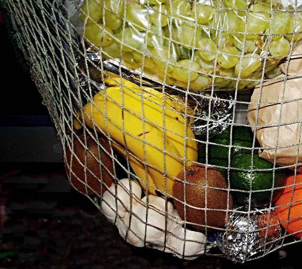 a mixed bag of colourful fruit hanging in a string basket. - garlic hanging string vegetable imagens e fotografias de stock