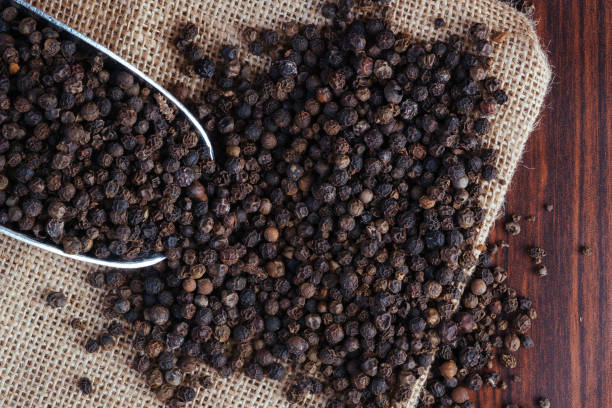 Black peppercorn top view on rustic sack Plenty whole black pepper with steel spoon and rustic sack black peppercorn photos stock pictures, royalty-free photos & images