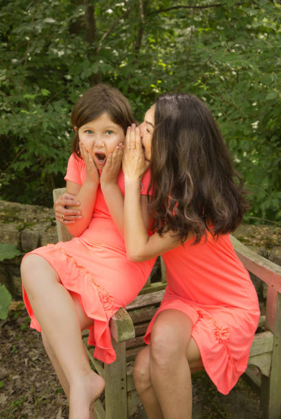 istock mom whisper a secret to her daughter 800934274