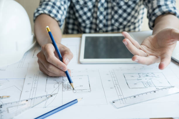 istock Architect working on real estate project at workplace. Male engineer hand working with living house blueprint at office. Business, people, construction and building concept 800945172
