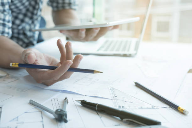 istock Architect working on real estate project at workplace. Male engineer hand working with digital tablet and living house blueprint at office. Business, people, construction and building concept 800945186