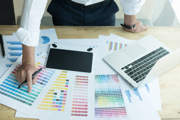 istock young graphic designer working with computer and color swatch. creative man using stylus pen and digital tablet at modern office. Architect using work tools and sample colour catalog. business, technology, design and people concept 800945232