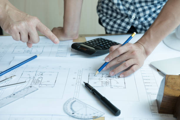 istock Architect working on real estate project with partner at workplace. Male engineer hand discussing with colleague on living house blueprint at office. Business, people, construction and building concept 800945250