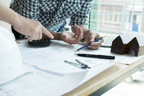 istock Architect working on real estate project with partner at workplace. Male engineer hand discussing with colleague on living house blueprint at office. Business, people, construction and building concept 800945260