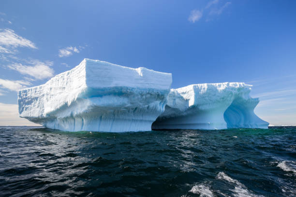 信じられないほど大規模な表の氷山が暗い南極海に浮かぶ - ice shelf ストックフォトと画像