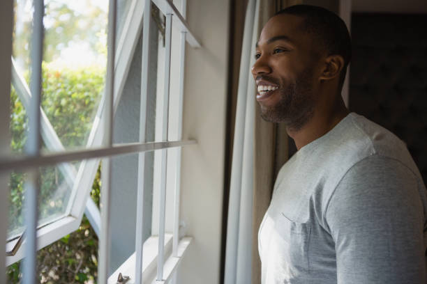 istock Thoughtful smiling man looking out through window at home 800992826