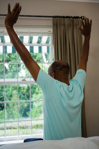 istock Rear view senior man stretching arms while sitting on bed 801006320