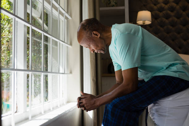 istock Senior man sitting by window in bedroom at home 801008414