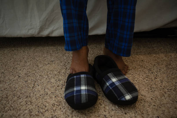 blue clogs on sunlit wooden floor, long dramatic shadow across textured boards, quiet domestic solitude after child's play, warm golden light revealing dust