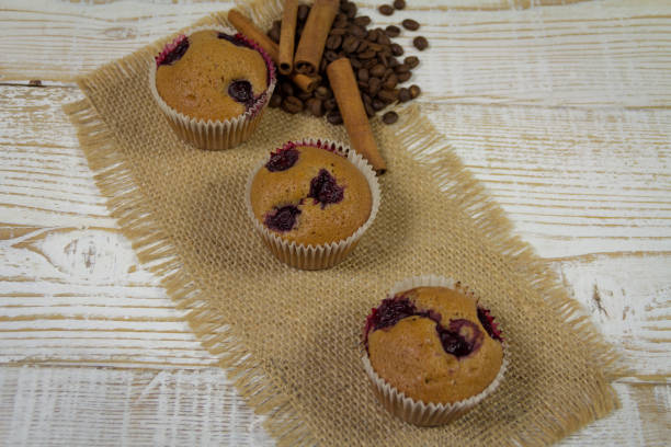 istock Delicious Muffins with cherry, cinnamon and coffee beans on wooden background 801030486