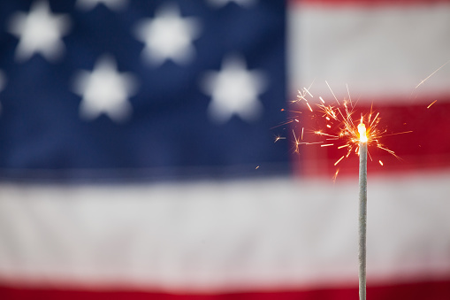 Close-up of sparklers burning against American flag background