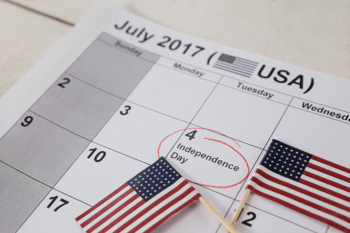 Close-up of American flags with fourth of july calendar