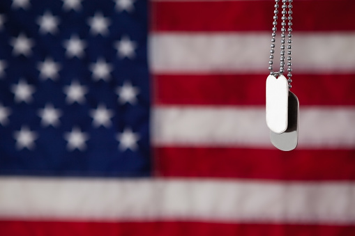 Close-up of dog tag hanging against American flag background