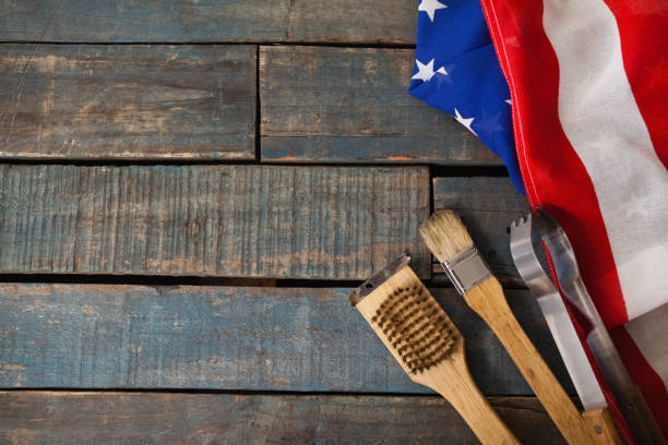 Basting brush and tong with American flag arranged on wooden table