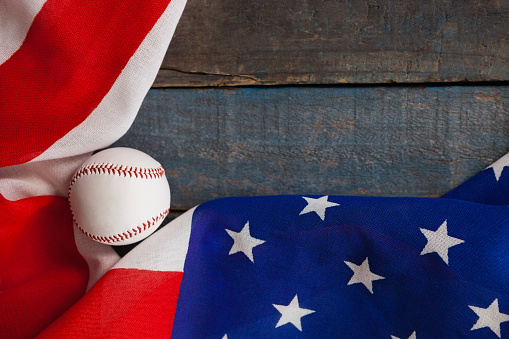 Overhead view of baseball and American flag on wooden table