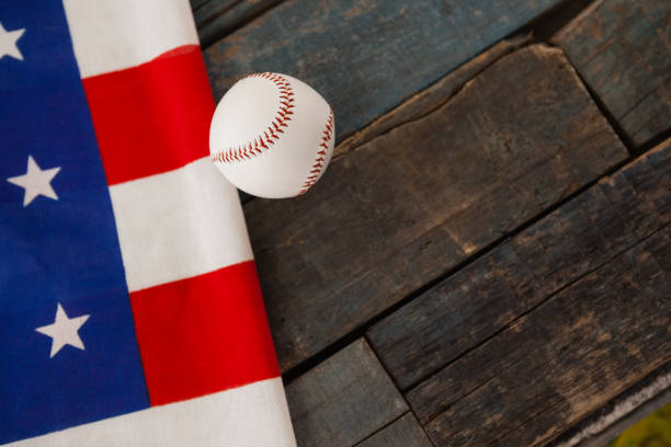 Close-up of baseball ball and American flag on wooden table