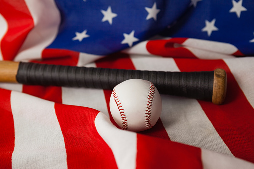 Close-up of baseball bat and ball on American flag