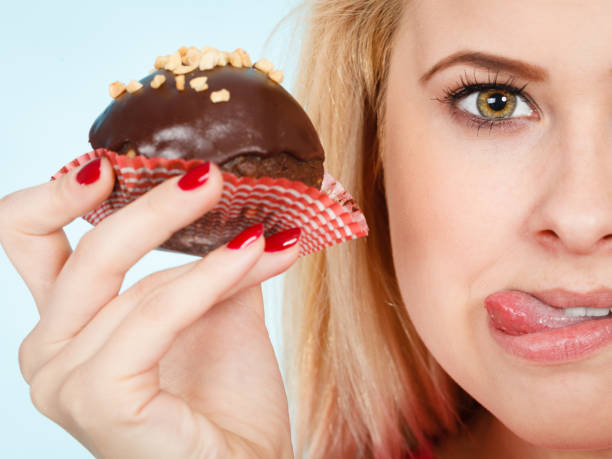 istock Woman holding chocolate cupcake about to bite 801089662