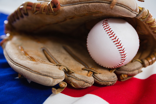 Close-up of baseball and gloves on an American flag
