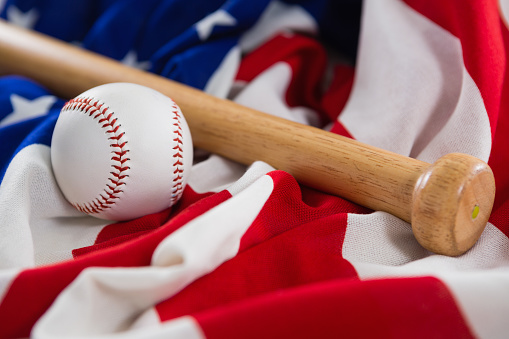 Close-up of baseball and baseball bat on an American flag