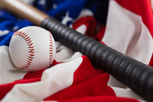 Close-up of baseball and baseball bat on an American flag