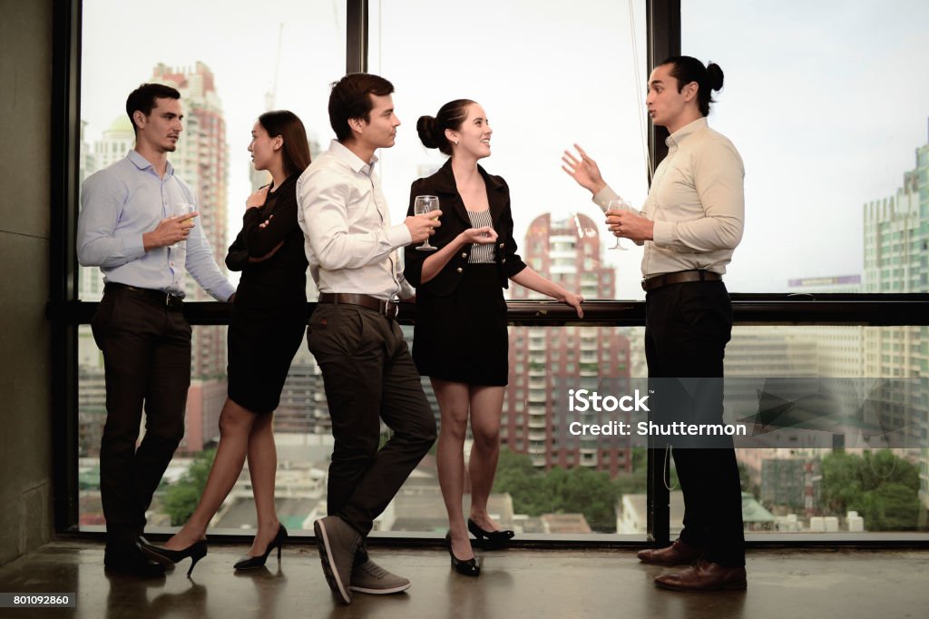 businessman and businesswoman are drinking champagne talking and smiling while celebrating in office, successful business concept. Drinking Water Stock Photo