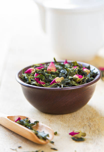 Green tea leaves blended with rose buds by tea pot