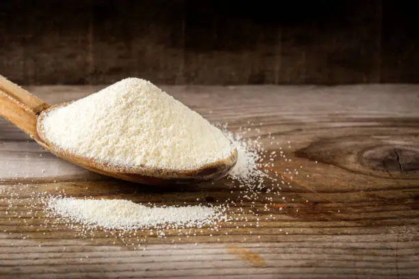 Organic semolina or couscous wheat in wooden spoon on wooden rustic  background.