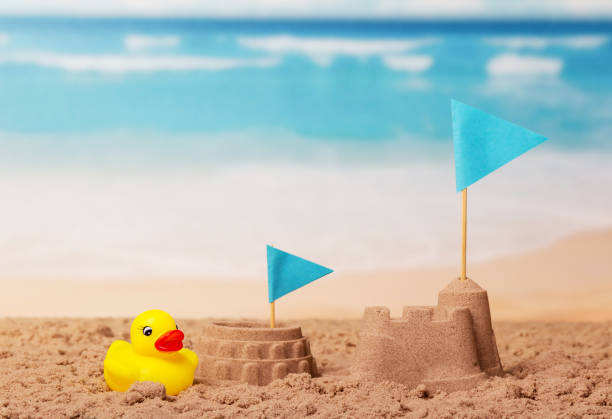 istock Coliseum and Tower of sand, blue flag, rubber duck on beach. 801109020