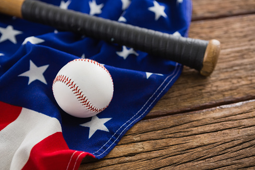 Close-up of baseball and bat on an American flag