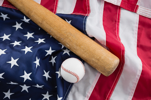 Close-up of baseball bat and ball on American flag