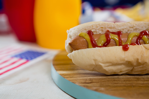Close-up of American flag and hot dog on wooden table