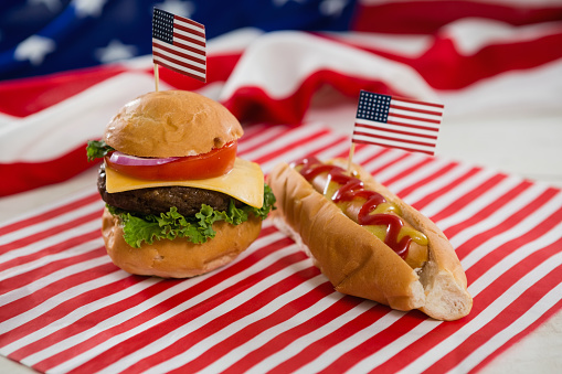 Close-up of American flag with hot dog and burger on wooden table