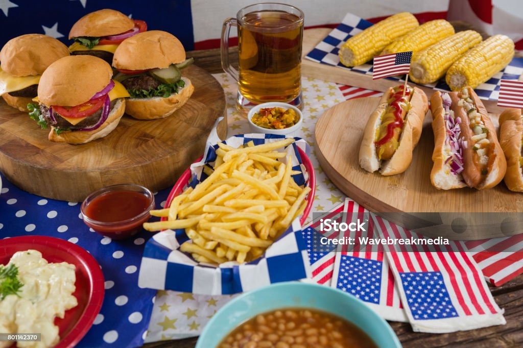 Hot dogs and burgers on wooden table with 4th july theme Close-up of hot dogs and burgers on wooden table with 4th july theme 70-79 Years Stock Photo