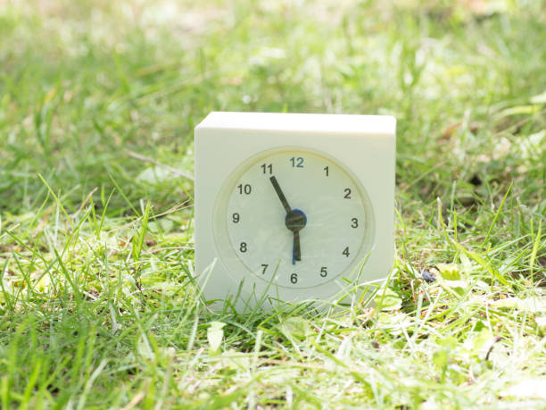 istock White simple clock on lawn yard, 5:55 five fifty five o'clock 801176558