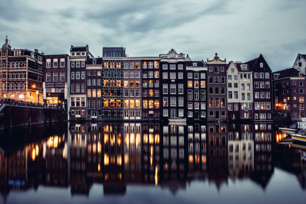 amsterdam huizen reflecties in de nacht op het water van het kanaal - grachtenpand stockfoto's en -beelden