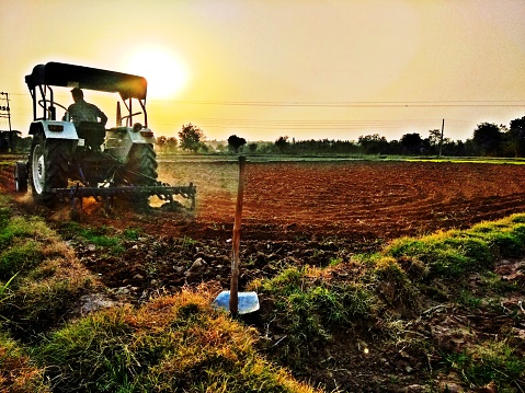beautiful sunset during ploughing of tractor