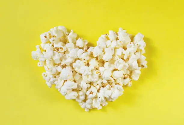 Photo of Heart shaped white fluffy popcorn on yellow