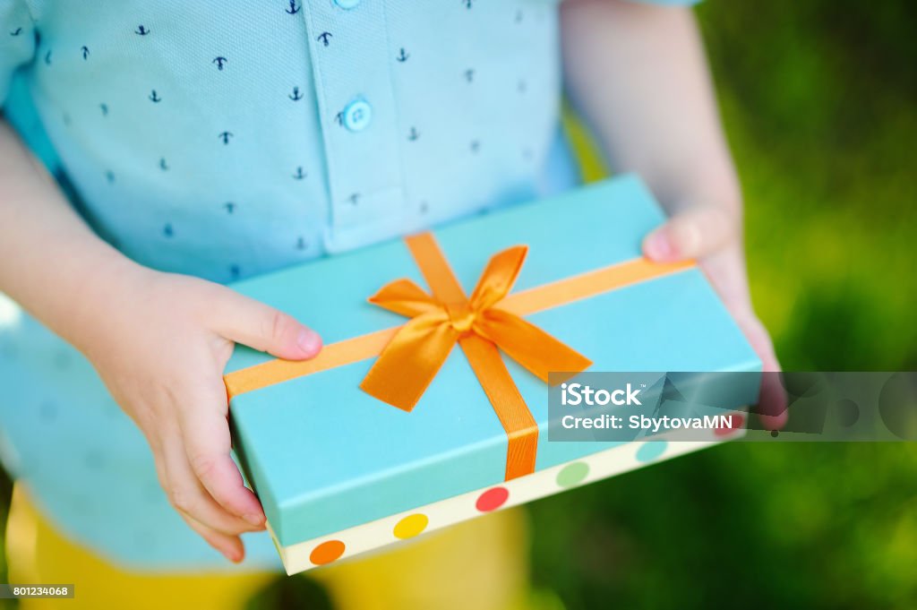 Close-up of nicely wrapped birthday gift being held by a child Close-up of nicely wrapped birthday gift being held by a child with no face visible. Party time concept Birthday Present Stock Photo