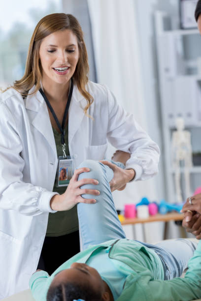 istock Female chiropractor bends young girl's leg 801244944