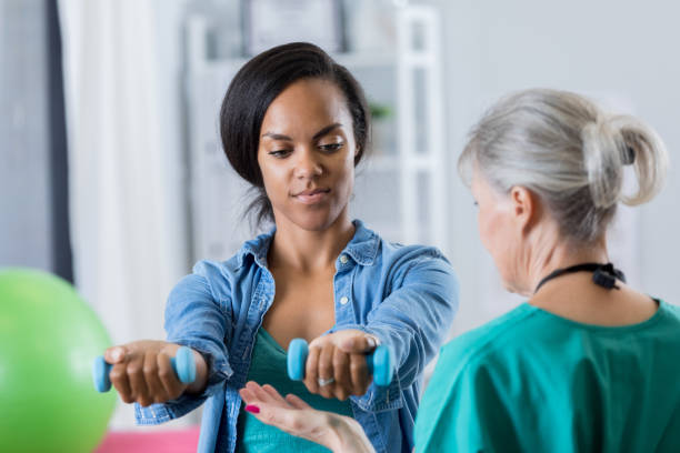 istock Senior physical therapist helps woman with hand weights 801244958