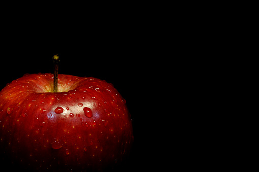 close-up of red apple, organic, on natural wood table with dark background, copy space