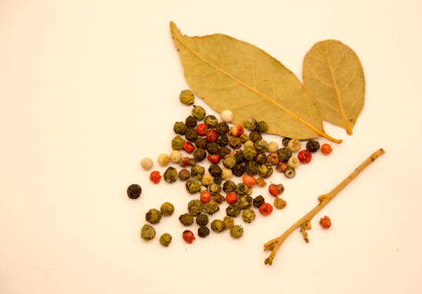 scattered grains of black pepper and bay leaves