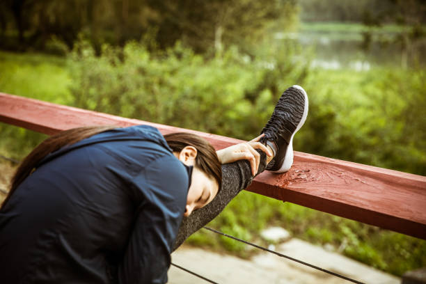 woman stretching legs with railing - railing beautiful human leg people imagens e fotografias de stock